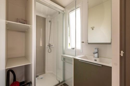 une salle de bain blanche avec une douche et un lavabo dans l'établissement Camping les Alouettes - Bretignolles-sur-Mer, à Bretignolles-sur-Mer