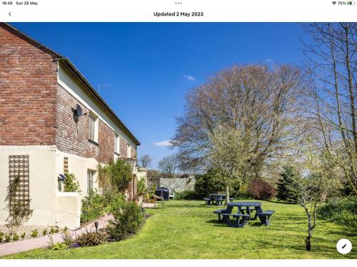 a yard with picnic tables and a brick building at Tatson Farmhouse B&B in Bridgerule