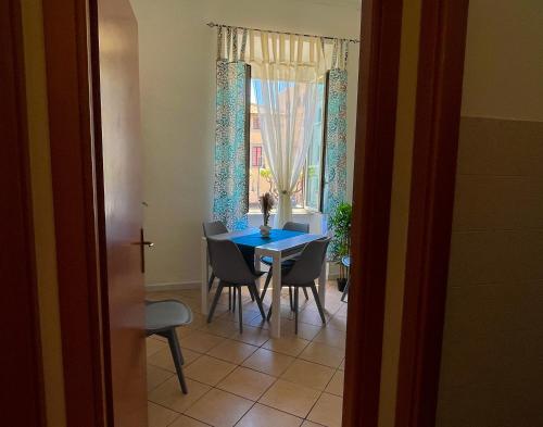 a dining room with a blue table and chairs and a window at NIMPHAEA BLUE APARTMENT - Elegant Central Flat, Walk to Beach & Train Station in Nettuno