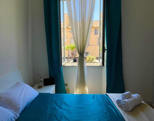 a bedroom with a blue bed and a window at NIMPHAEA BLUE APARTMENT - Elegant Central Flat, Walk to Beach & Train Station in Nettuno