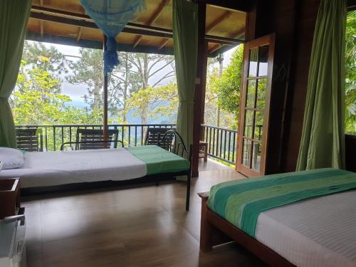two beds in a room with a balcony at Ella Mount Relax Cottage in Ella