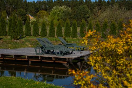 a group of chairs sitting on a dock next to the water at Greenery Kupolai in Kalveliai