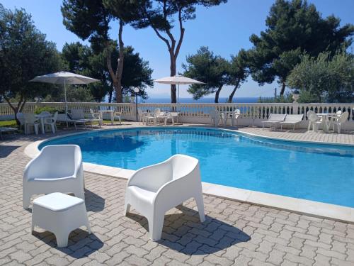 a swimming pool with white chairs and tables at Villa Nunziatella Badia in Trappeto