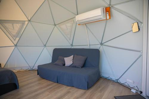a room with a blue couch in a triangular wall at Greenery Kupolai in Kalveliai
