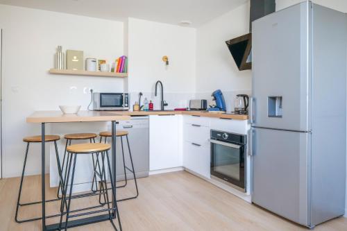 La cuisine est équipée d'un réfrigérateur et d'un comptoir avec tabourets. dans l'établissement Très bel appartement lumineux et au calme - 2 personnes, à Angers