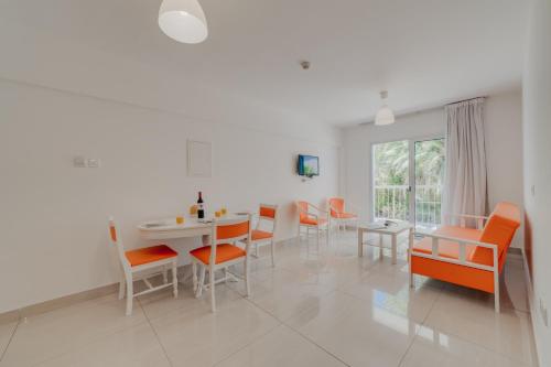 a dining room with orange chairs and a white table at Christos Napa Self Serviced Apartments in Ayia Napa