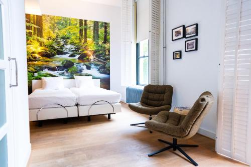 a bedroom with a bed and two chairs at Hotel Villa Ruimzicht in Doetinchem