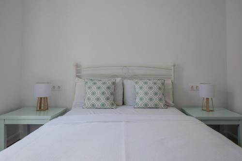 a bedroom with a white bed with two end tables at Vine House Apartments in Kassiopi