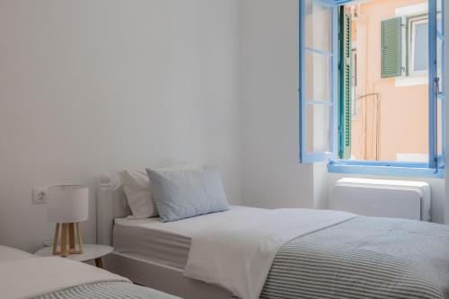 a white bedroom with a bed and a window at Vine House Apartments in Kassiopi