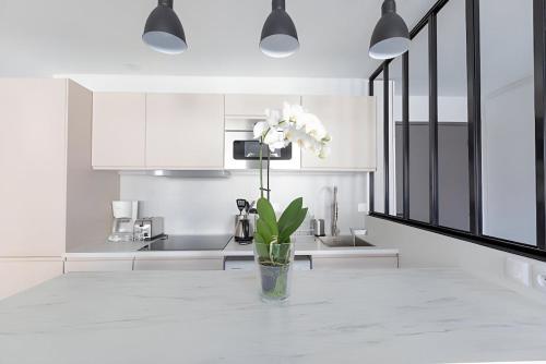 un vase avec des fleurs sur une table dans une cuisine dans l'établissement Paris 15 Tour-Eiffel Bd Grenelle - 2 rooms, à Paris