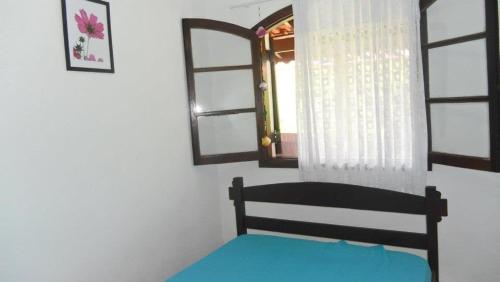 a bedroom with a bed in a room with windows at Chale Colonial in Ubatuba