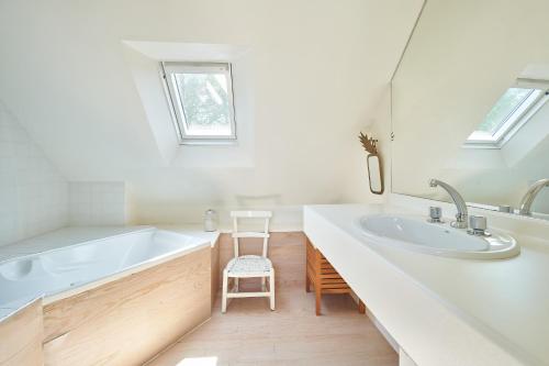 une salle de bain blanche avec une baignoire et un lavabo dans l'établissement Longère de charme, Mousterlin, à Fouesnant