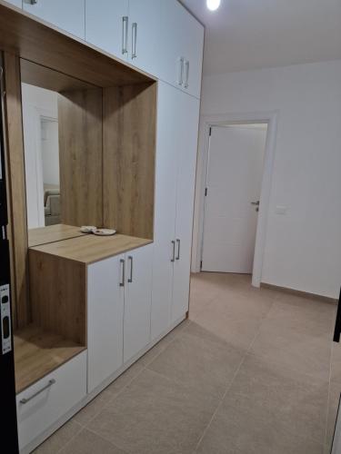 a kitchen with white cabinets and a large mirror at AURORA Apartment Shëngjin Kune in Shëngjin
