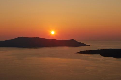 フィラにあるCaldera's Bliss Suitesの山を背景に海上の夕日
