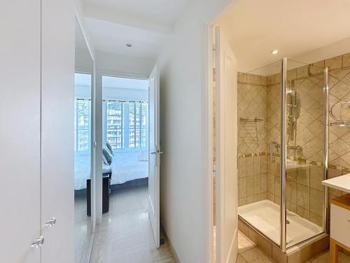 Elle comprend un lit et une salle de bains blanche pourvue d'une douche. dans l'établissement Beachfront 2-bedroom apartment with balcony, à Cannes