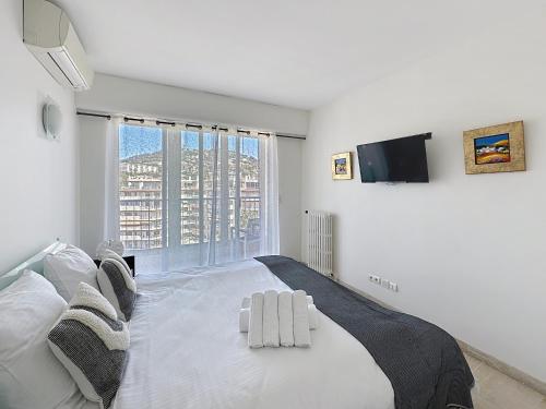 - une chambre blanche avec un grand lit et une télévision dans l'établissement Beachfront 2-bedroom apartment with balcony, à Cannes