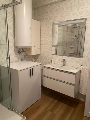 a white bathroom with a sink and a mirror at Casa centro histórico de Viveiro in Viveiro