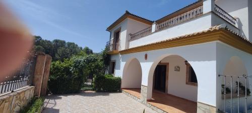 a white house with an archway and a fence at Lake View Villa in Iznájar