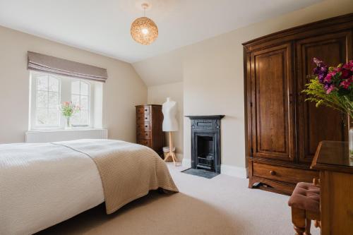 a bedroom with a bed and a fireplace at Herdsman's Cottage - Beautiful 3 Bed in Wiltshire! in Sherston
