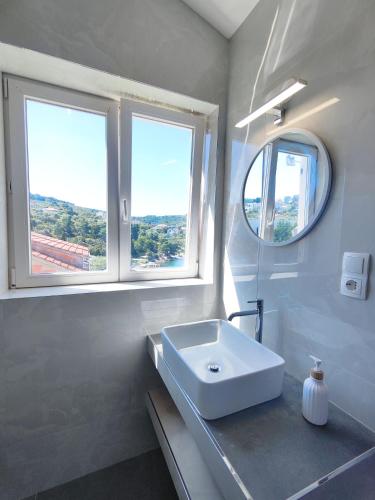 a white bathroom with a sink and two windows at Villa Paris in Nečujam