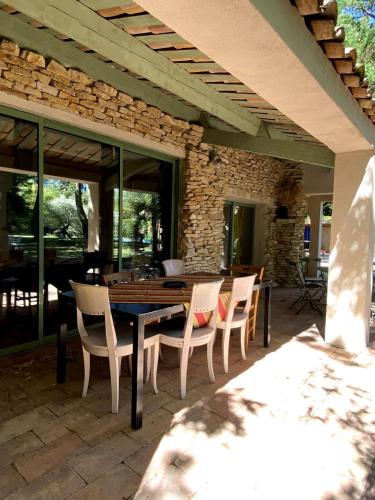 un patio avec une table et des chaises et un mur en pierre dans l'établissement Maison entière 5 min du centre d'Avignon, aux Angles (Gard)