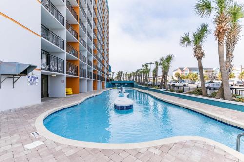 a swimming pool in front of a building with palm trees at Oceanview Condo Pool Steps to Beach Hot Tubs in Myrtle Beach