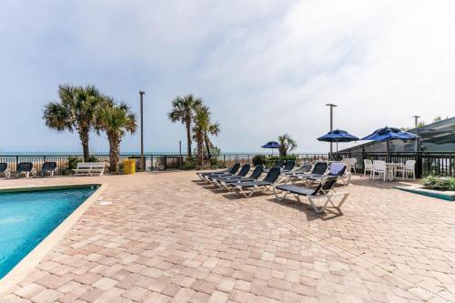 a pool with chairs and umbrellas next to the ocean at Oceanview Condo Pool Steps to Beach Hot Tubs in Myrtle Beach