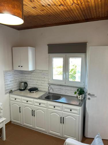 a kitchen with white cabinets and a sink at Christodoulos Apartment in Agios Georgios