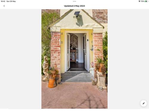 a home with a yellow door and a brick building at Tatson Farmhouse B&B in Bridgerule