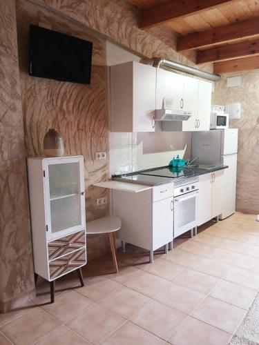 a kitchen with white cabinets and a tv on the wall at Casa Estrella in Villafamés