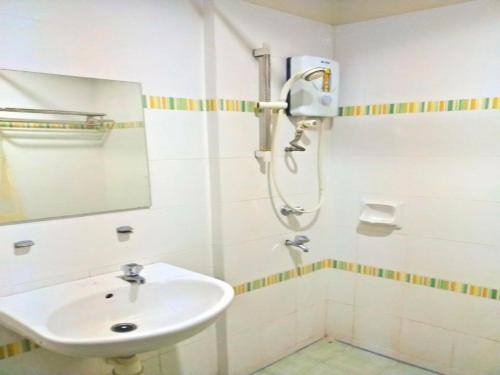 a white bathroom with a sink and a shower at Capital O Suria Urban Escape in Kampong Selemat