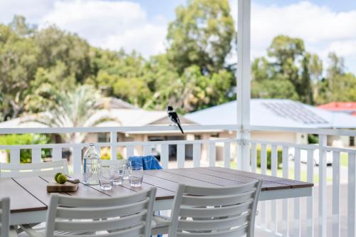 a bird perched on a wooden table on a porch at Biirinba in Yamba
