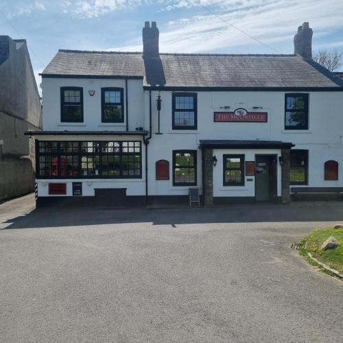 a white building with a sign in front of it at The Mcorville Inn in Elwick