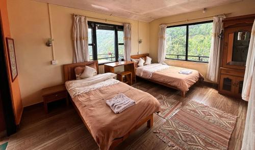 una camera d'albergo con due letti e una finestra di Siddhartha Garden Ayurveda a Pokhara