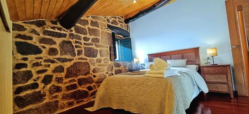 a bedroom with a stone wall with a bed in it at Luz do Sil in Ourense