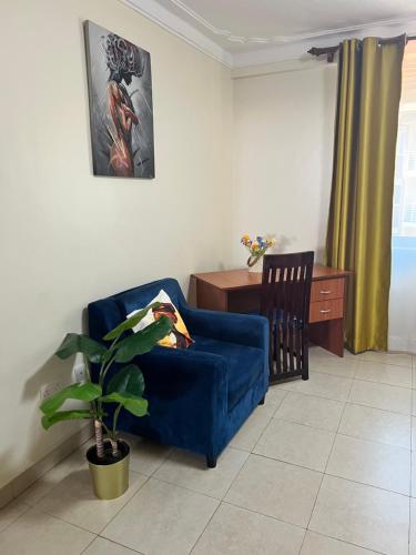 a living room with a blue couch and a desk at Kamona Living 3 Zimmer Apartment in Namugongo