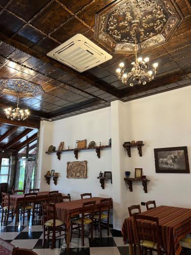 a restaurant with wooden tables and chairs and chandeliers at Hotel Kaceli in Berat