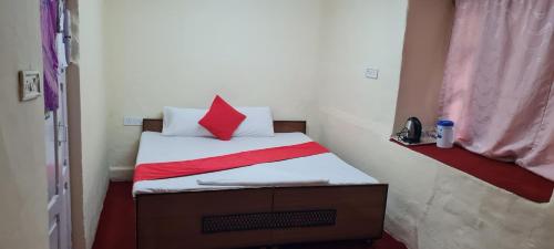 a small bedroom with a bed with a red pillow at The Heritage jasmine lodge B&B in Shimla