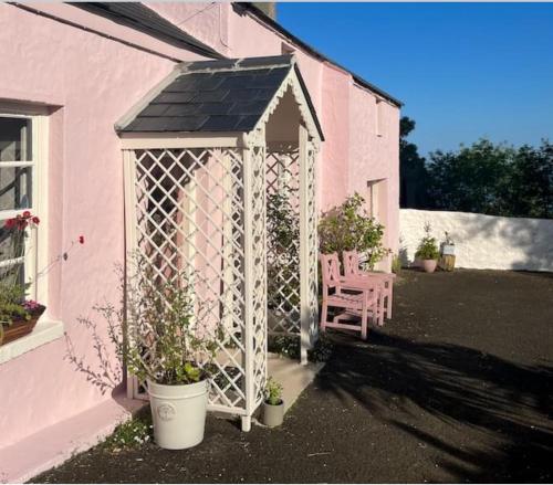 ein weißer Pavillon an der Seite eines rosa Hauses in der Unterkunft The Pink Cottage upstairs suite & Garden Summer Room in Whitehead