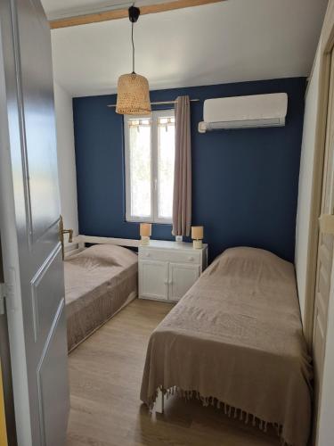 - une chambre bleue avec 2 lits et une fenêtre dans l'établissement maison au cœur des vignes, à Monbazillac