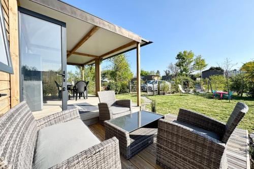 d'une terrasse avec des chaises en osier et une table en verre. dans l'établissement Charmant Bungalow Neuf Terrasse Jardin au calme, à La Celle-sous-Gouzon