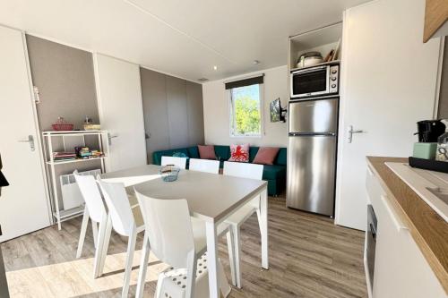 une cuisine et un salon avec une table et des chaises dans l'établissement Charmant Bungalow Neuf Terrasse Jardin au calme, à La Celle-sous-Gouzon