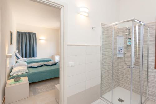 a bathroom with a shower and a bed at Domo Davide in San Teodoro