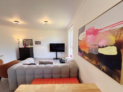 a living room with a white couch and a tv at Quiet 2 bedrooms and 2 bathrooms with free parking in Edinburgh