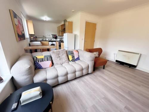 a living room with a white couch and a kitchen at Quiet 2 bedrooms and 2 bathrooms with free parking in Edinburgh