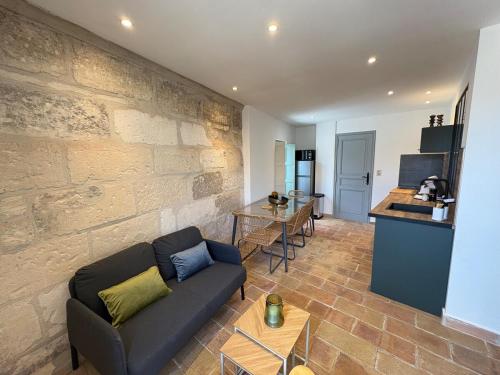 un salon avec un canapé et un mur en pierre dans l'établissement Chez Balthazar n3 Arles centre, à Arles
