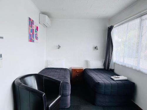 a room with a bed and a chair and a window at Brooklyne Motel Sanson in Sanson