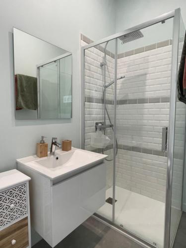 une salle de bain blanche avec un lavabo et une douche dans l'établissement Aux portes des iles, à Saint-Just