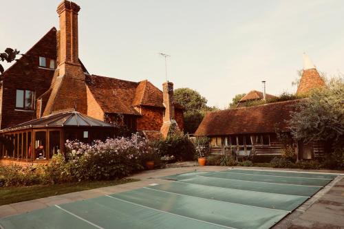 a tennis court in front of a house at Cart Shed Heaven in Sissinghurst