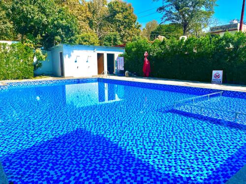 a woman in a red dress standing next to a swimming pool at The Woods Farmhouse Resort, Jim Corbett - A beautiful wellness resort in the lap of nature in Rāmnagar